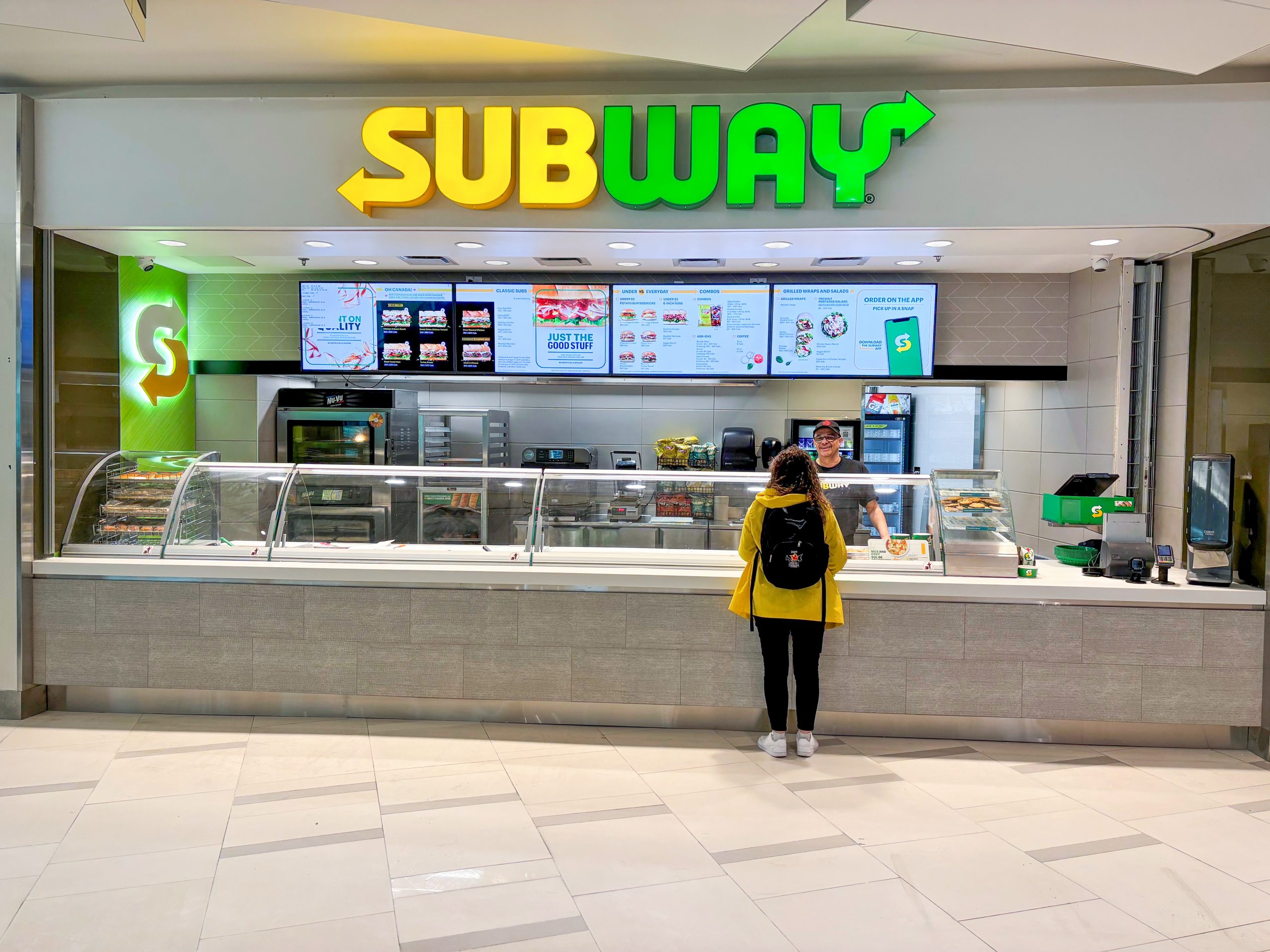 A person standing in front of a Subway counter