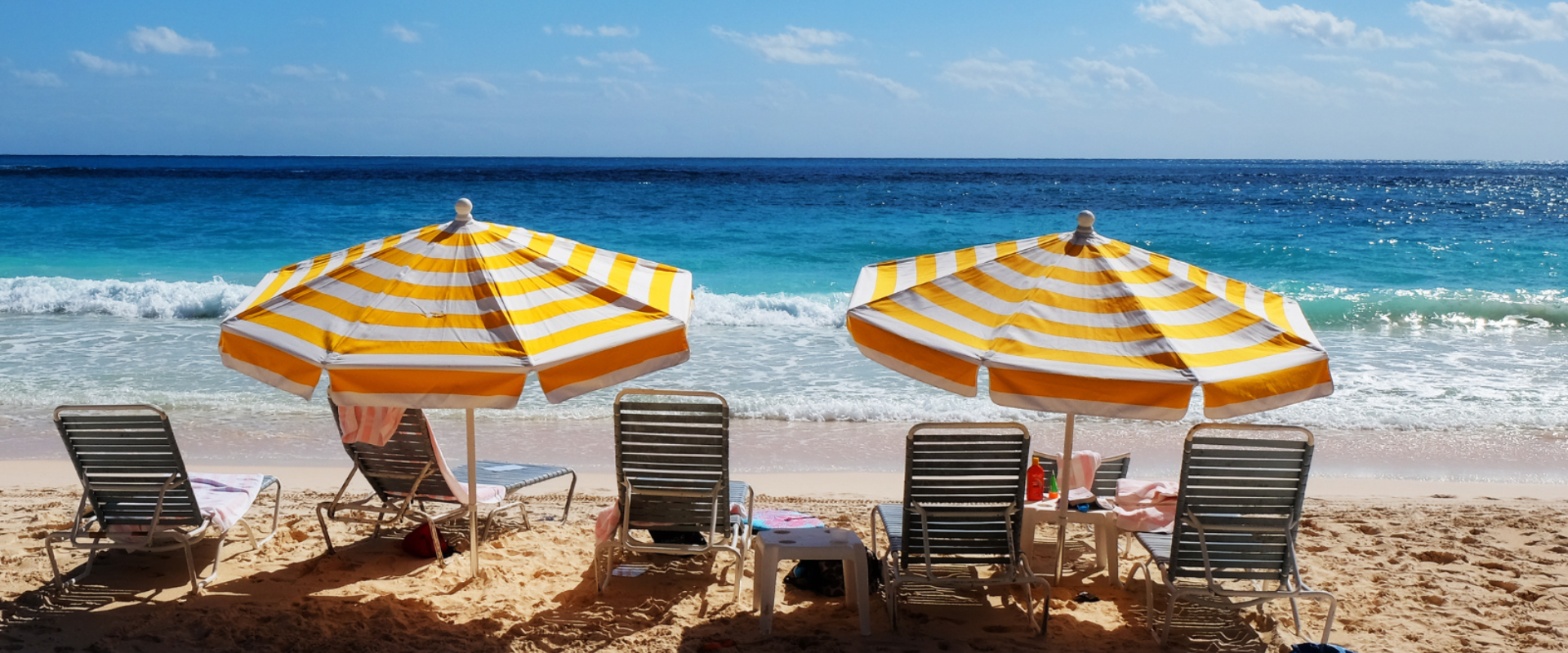 A photo of two umbrellas on the beach beside the shore