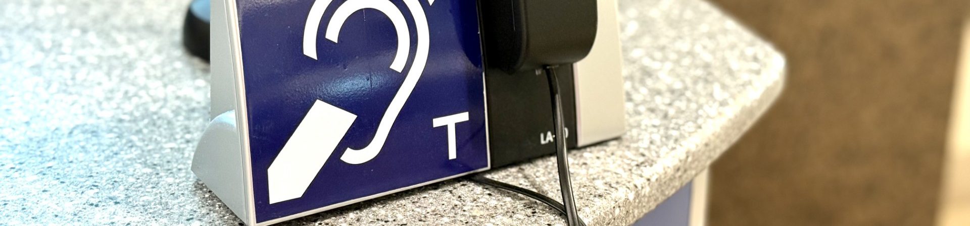 A photo of a hearing loop sign atop a desk